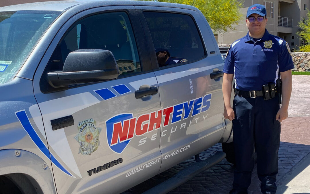 A security guard standing next to a Night Eyes Security truck in El Paso.